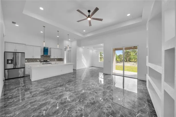 Unfurnished living room with marble finish floor, a tray ceiling, a high ceiling, and baseboards