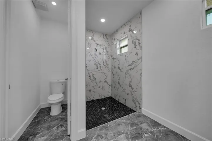 Full bath with marble finish floor, baseboards, toilet, and a marble finish shower