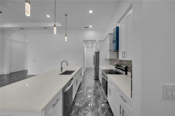 Kitchen featuring recessed lighting, stainless steel appliances, a sink, marble finish floor, and decorative backsplash