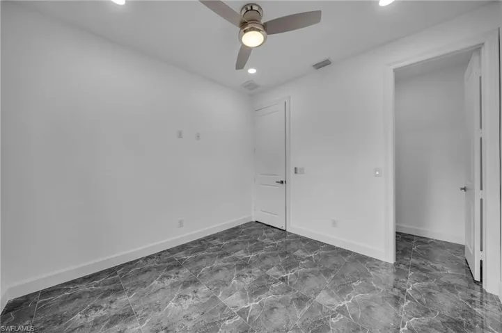 Unfurnished bedroom with marble finish floor, baseboards, visible vents, and ceiling fan