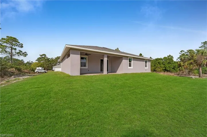 Rear view of house featuring a patio area, stucco siding, a yard, and ceiling fan