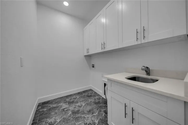 Laundry area with baseboards, a sink, cabinet space, and hookup for a washing machine