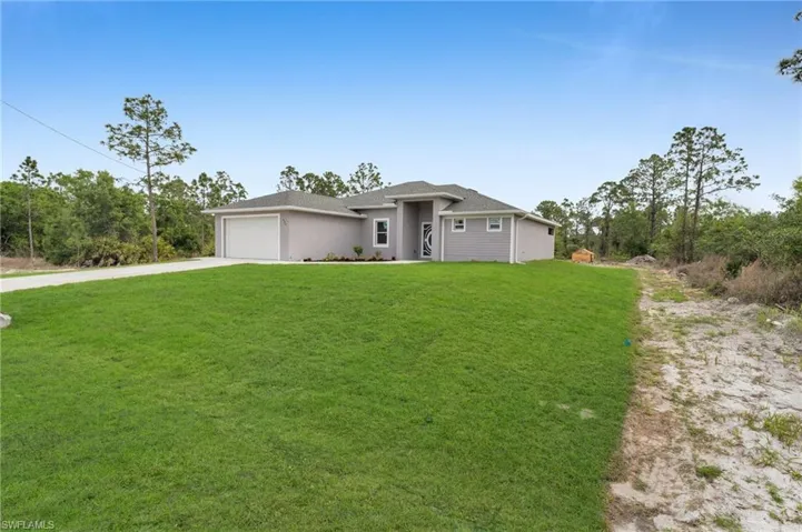 View of front of home with a garage, a front yard, and driveway