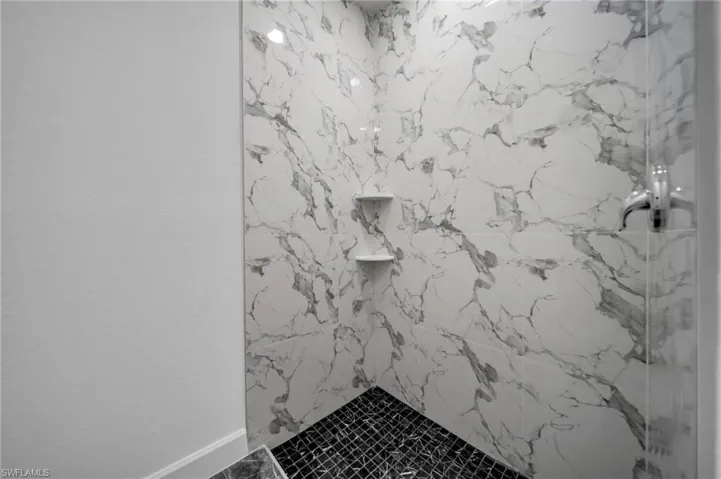 Room details featuring a marble finish shower