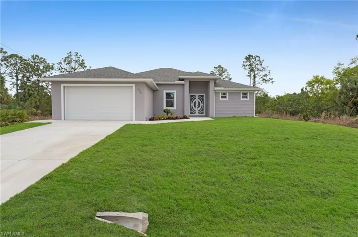 Prairie-style house featuring a garage, concrete driveway, a front yard, and stucco siding