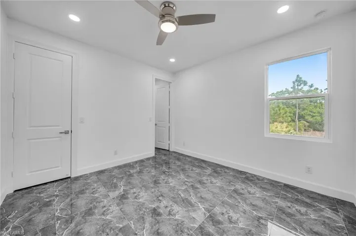 Unfurnished bedroom with recessed lighting, marble finish floor, and baseboards