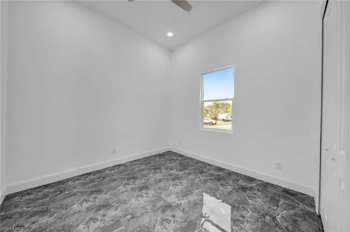 Empty room featuring marble finish floor, baseboards, a ceiling fan, and recessed lighting