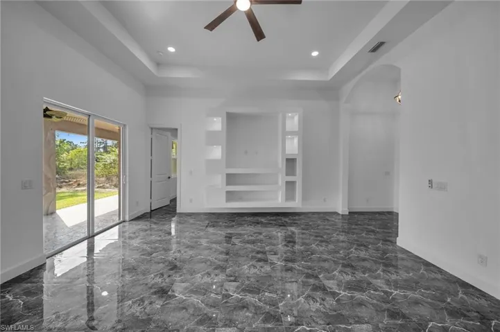 Unfurnished living room with baseboards, visible vents, arched walkways, ceiling fan, and marble finish floor