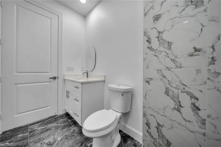 Bathroom featuring marble finish floor, baseboards, vanity, and toilet