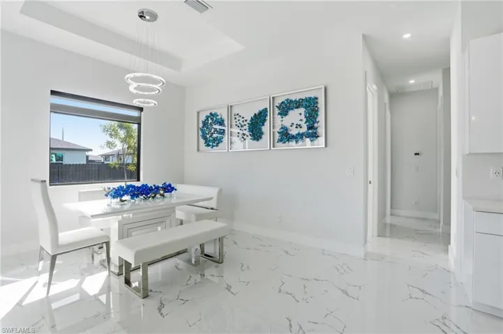 Dining room featuring light marble finish flooring and a raised ceiling