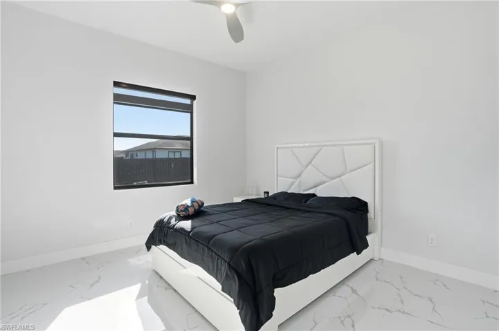 Bedroom with a ceiling fan and light marble finish floors