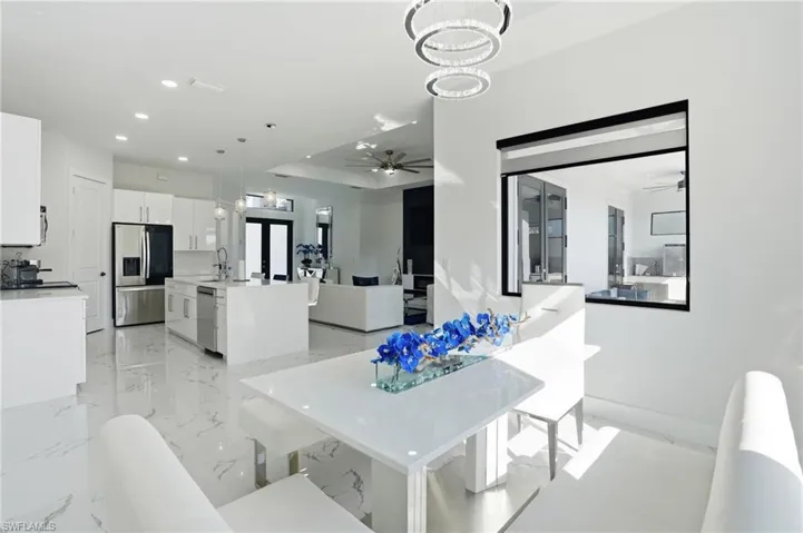 Dining area with a ceiling fan, hanging lights, and light marble finish floors