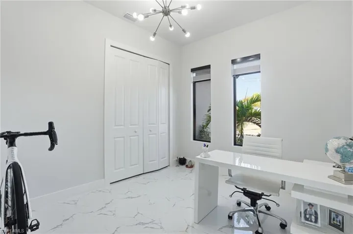 Home office with suspended lighting and light marble finish flooring