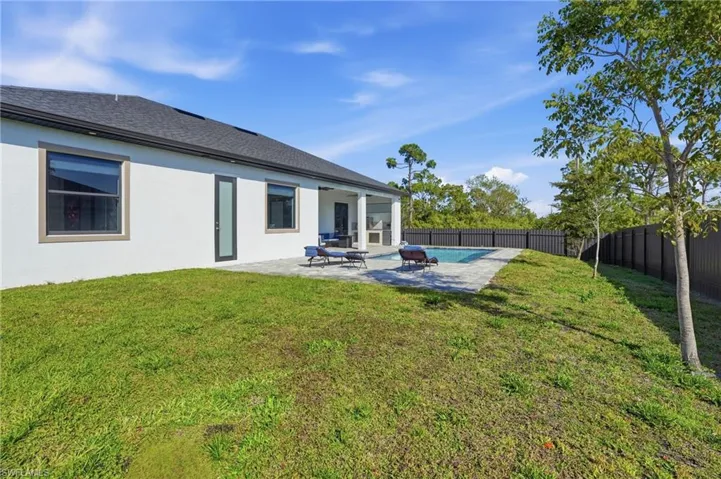 Rear view of house with a fenced backyard, a patio area, stucco siding, and a shingled roof