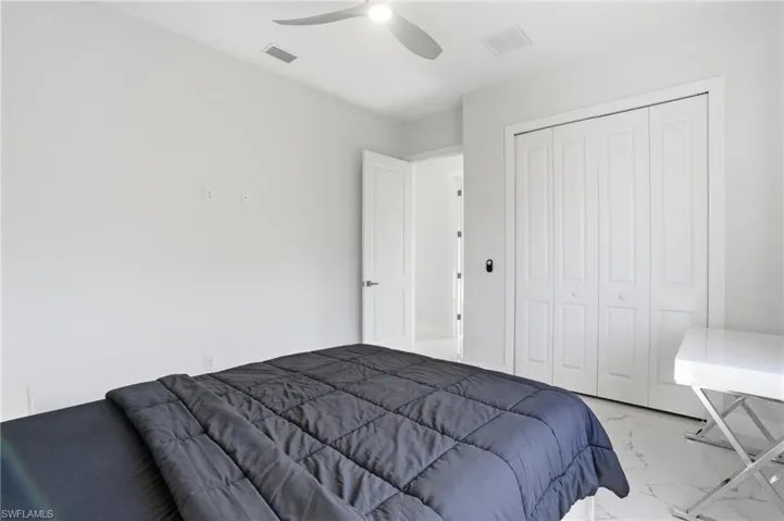 Bedroom featuring light marble finish floors, a closet, and ceiling fan