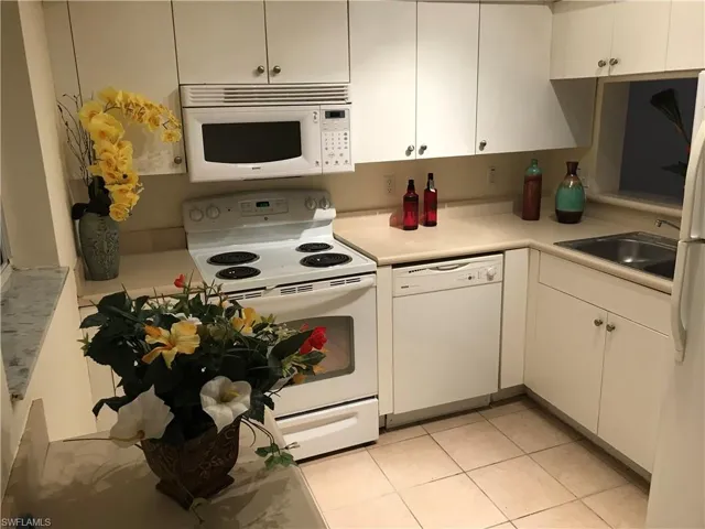 Kitchen featuring white appliances, light countertops, and white cabinets