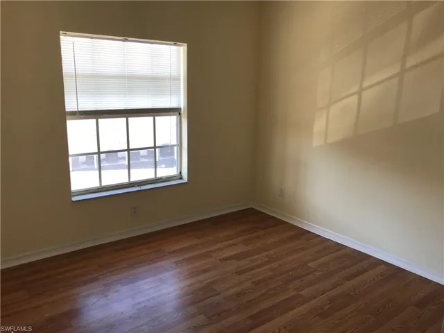 Unfurnished room featuring dark wood-style flooring and baseboards