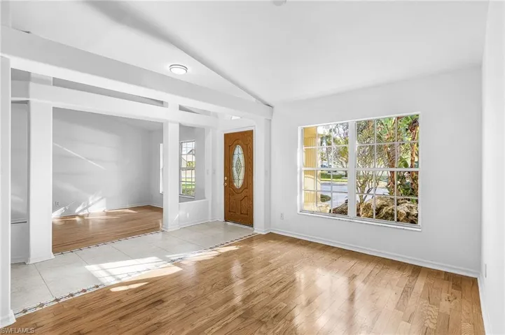 Foyer entrance with light wood finished floors and vaulted ceiling