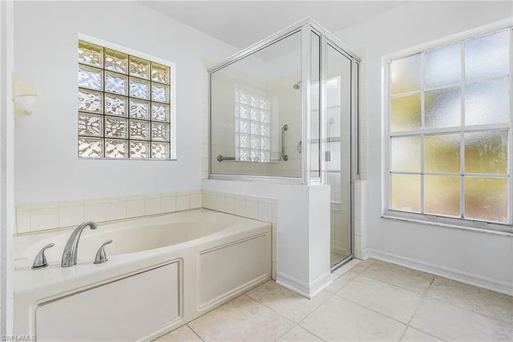Bathroom featuring a shower stall, a bath, light tile patterned flooring, and healthy amount of natural light