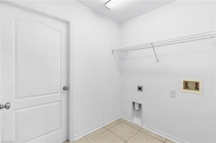 Laundry room with electric dryer hookup, light tile patterned flooring, and washer hookup
