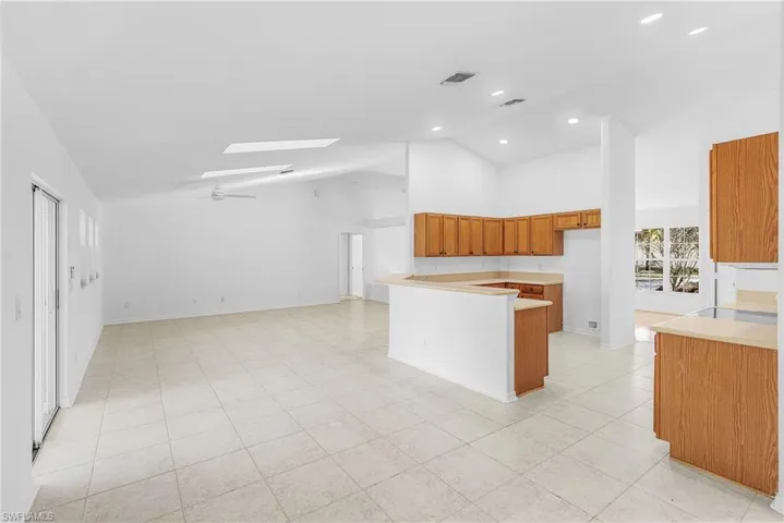 Kitchen featuring a peninsula, a skylight, wood finish cabinets, open floor plan, and vaulted ceiling