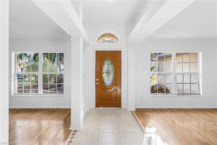 Foyer entrance featuring light tile patterned flooring, plenty of natural light, inlaid floor details, and a high ceiling