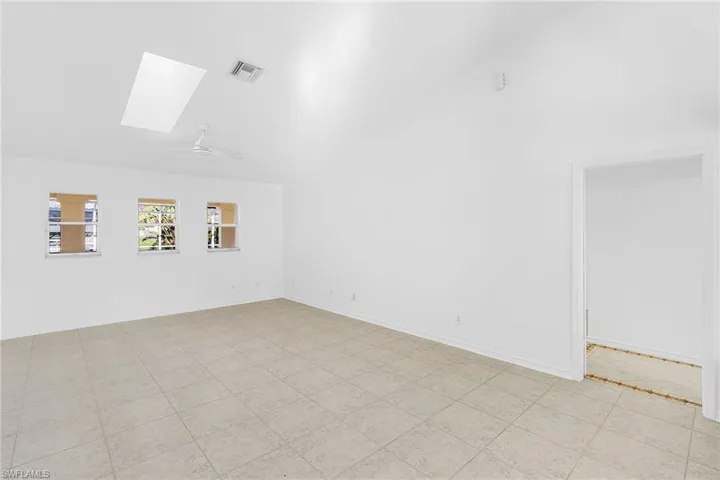Empty room featuring vaulted ceiling, a skylight, and ceiling fan