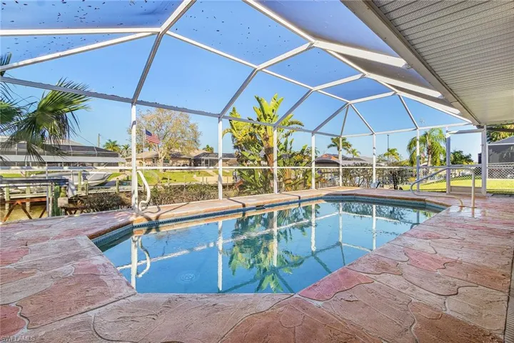 Outdoor pool featuring a sunroom, glass enclosure, and a patio
