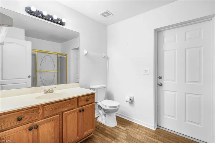 Bathroom featuring vanity, light wood-style flooring, and a marble finish shower