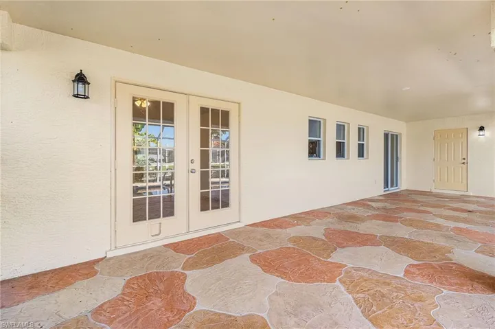 Property entrance with french doors, stucco siding, and a patio area