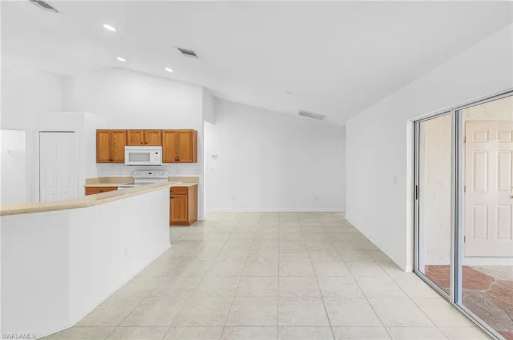 Kitchen with wood finish cabinets, light countertops, vaulted ceiling, and white appliances