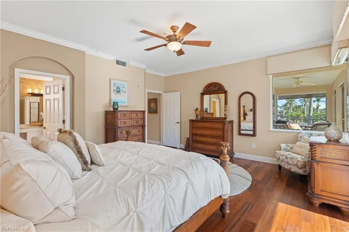Bedroom with crown molding, a ceiling fan, dark wood-style floors, baseboards, and visible vents