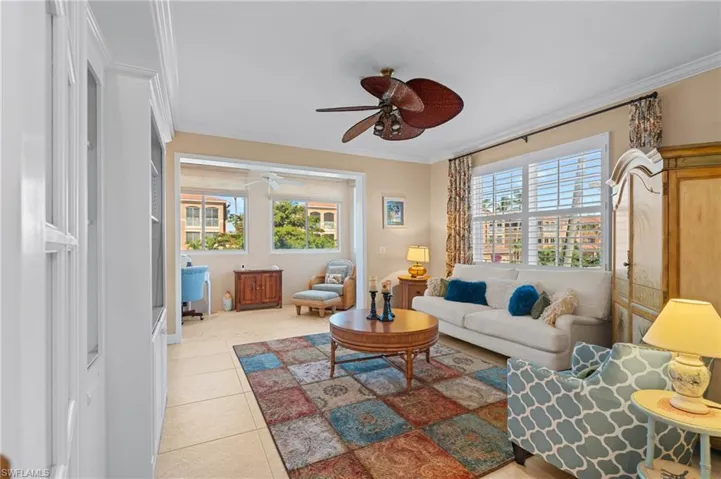 Living room featuring crown molding, ceiling fan, and light tile patterned floors