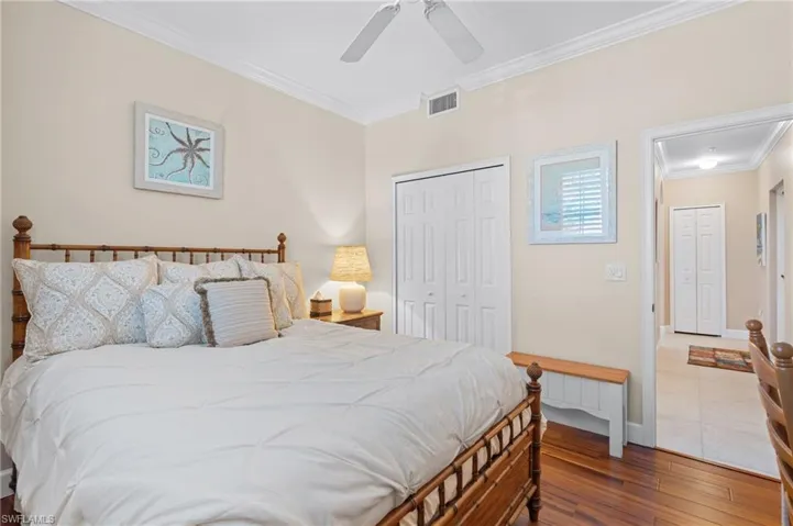 Bedroom featuring crown molding, a closet, baseboards, visible vents, and hardwood / wood-style floors