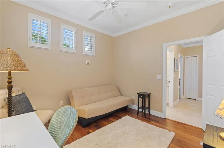 Home office with baseboards, wood finished floors, ornamental molding, and a ceiling fan
