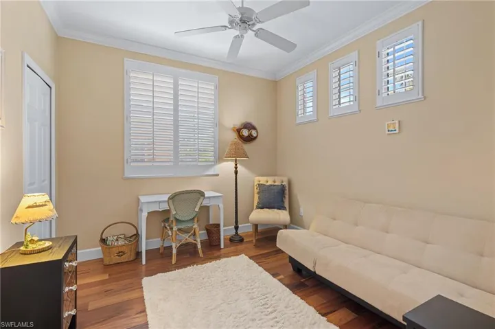 Home office featuring baseboards, crown molding, wood finished floors, and a ceiling fan