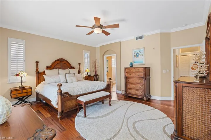 Bedroom featuring wood finished floors, crown molding, multiple windows, and visible vents