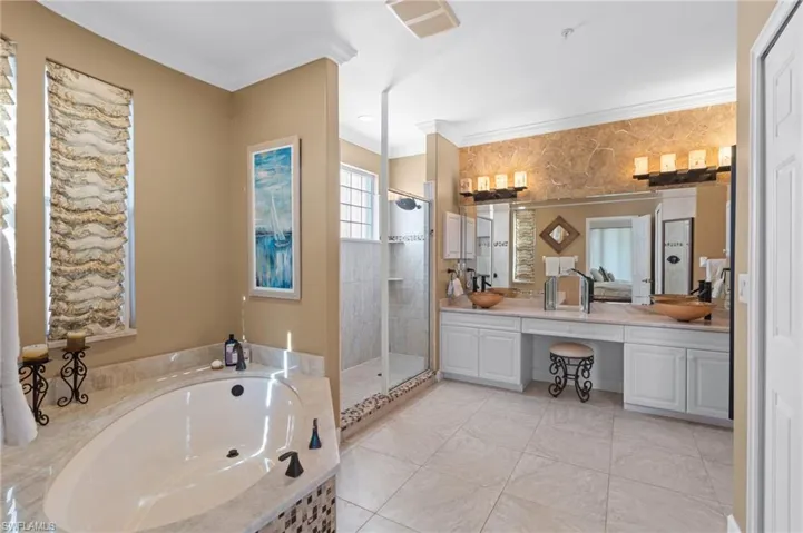 Full bath featuring tiled shower, a sink, a garden tub, ornamental molding, and double vanity