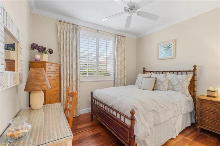 Bedroom featuring baseboards, ornamental molding, wood finished floors, and a ceiling fan
