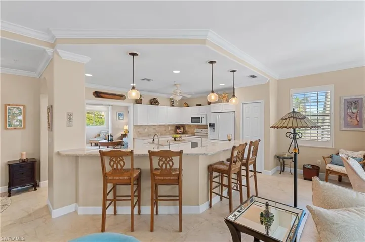 Kitchen featuring plenty of natural light, white appliances, a kitchen bar, and a peninsula