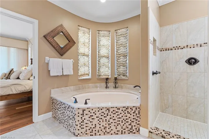 Ensuite bathroom featuring crown molding, baseboards, a garden tub, walk in shower, and ensuite bathroom