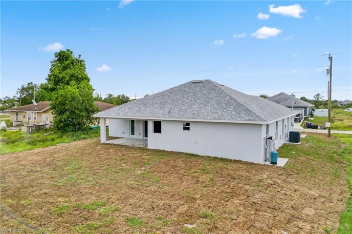 Back of house with a patio area, central AC unit, and a yard