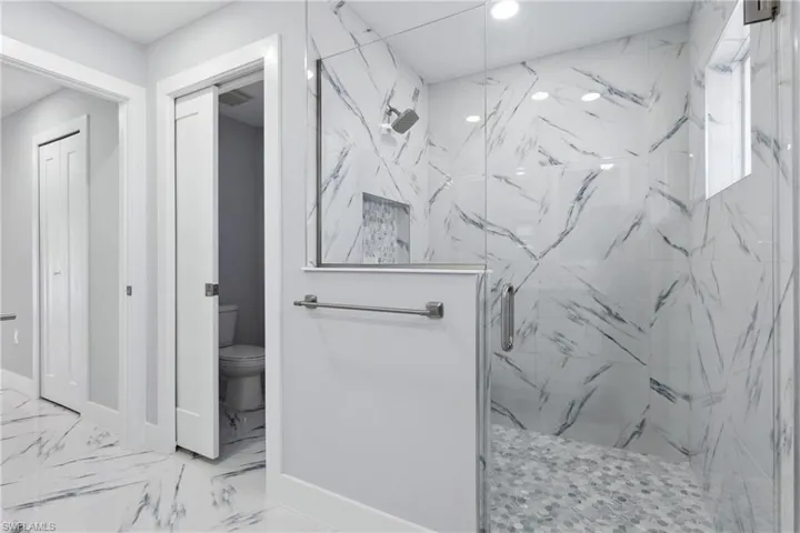 Bathroom with walk in shower, tile flooring, and toilet