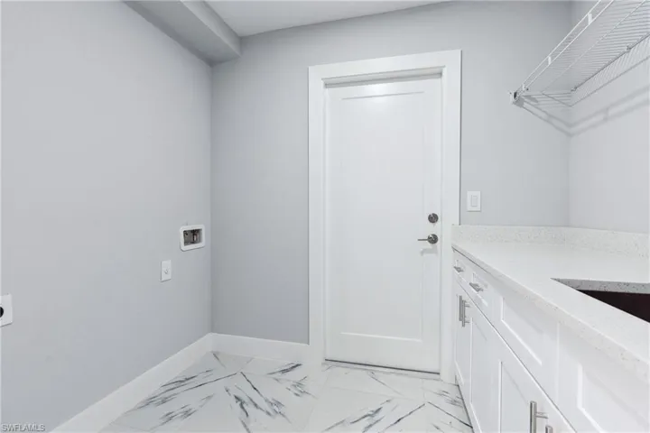 Clothes washing area featuring cabinets, hookup for a washing machine, light tile floors, and electric dryer hookup