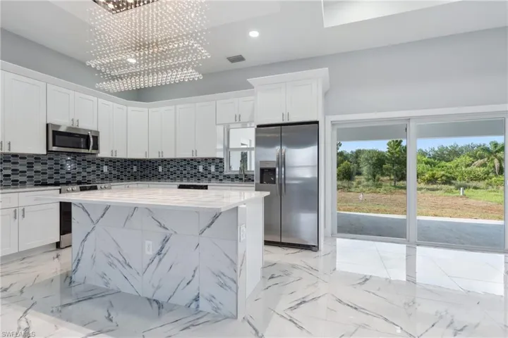 Kitchen with a center island, light stone counters, white cabinets, and appliances with stainless steel finishes