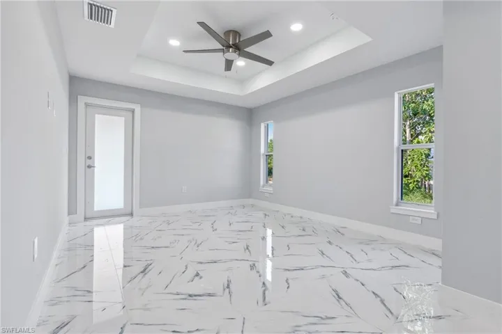 Tiled empty room with a tray ceiling and ceiling fan