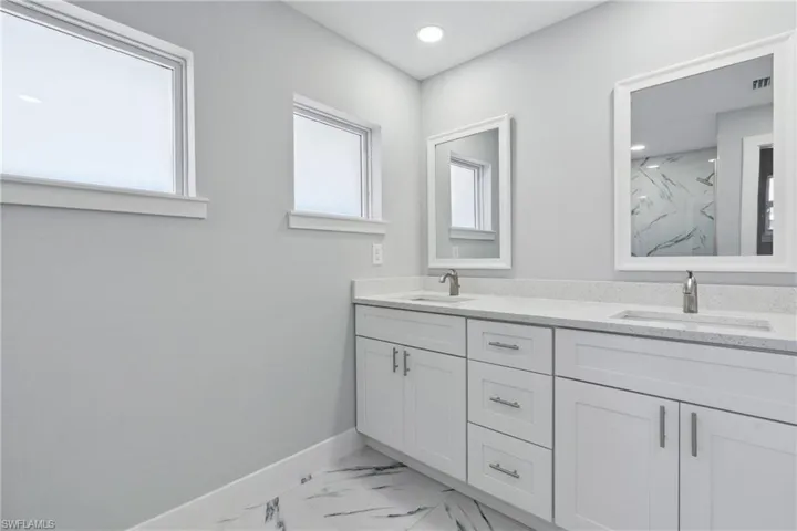 Bathroom featuring dual vanity, plenty of natural light, and tile flooring