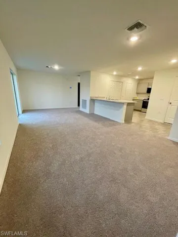 Unfurnished living room featuring light colored carpet and recessed lighting