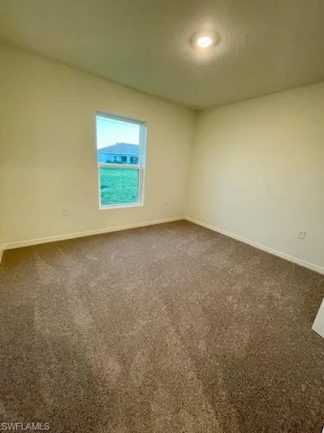 Carpeted spare room with a textured ceiling and baseboards