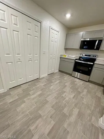 Kitchen with gray cabinets, light countertops, stainless steel appliances, and light wood-style flooring